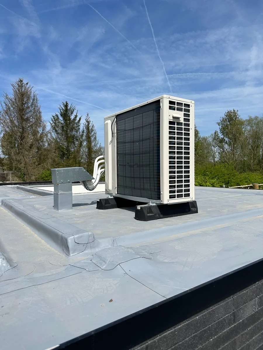 Grote Panasonic buitenunit op plat dak met leidingen