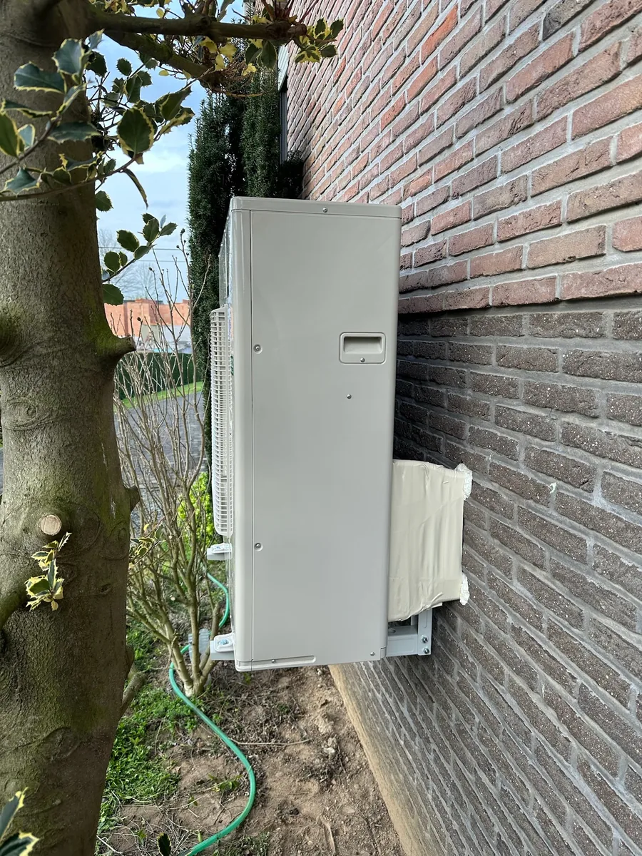 Panasonic buitenunit naast tuinmuur met beugel