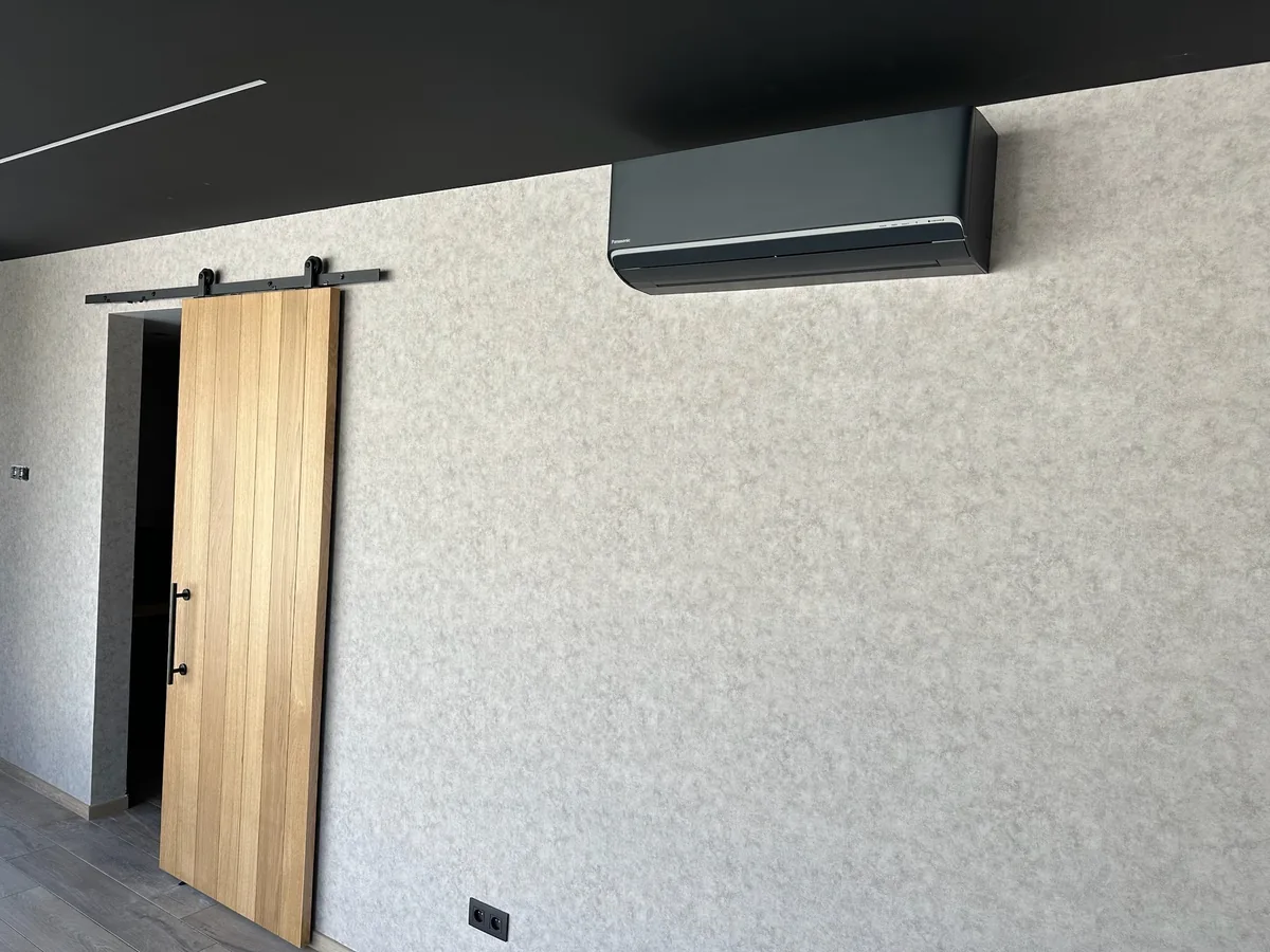 Zwarte Panasonic wandunit in moderne woonkamer met schuifdeur